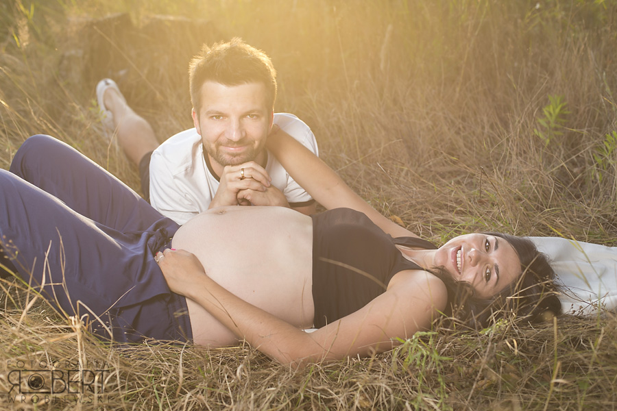 Partner obejmujący brzuch ciążowy - plener fotograficzny
